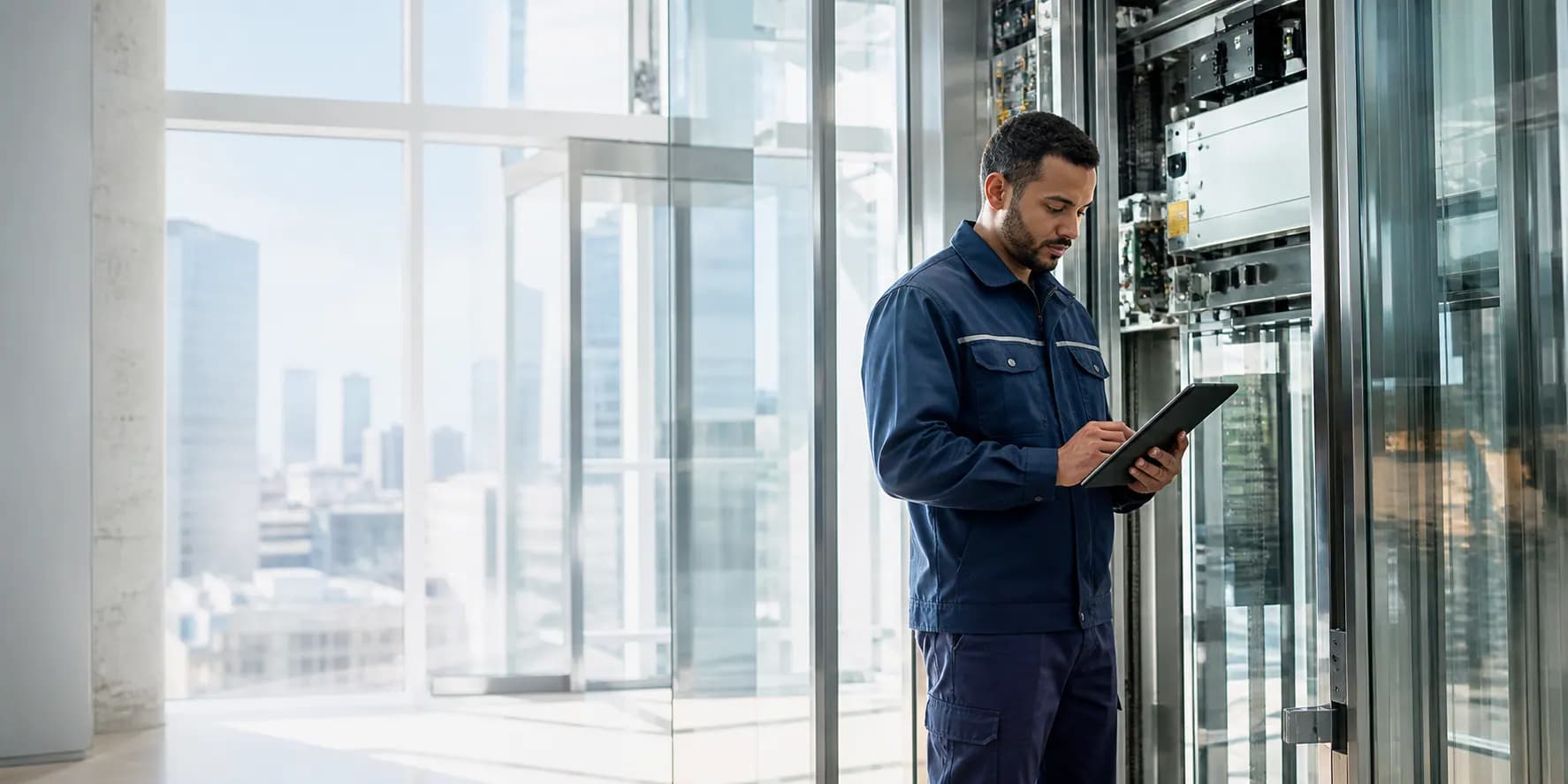 Elevator technician inspecting a modern lift system with a tablet